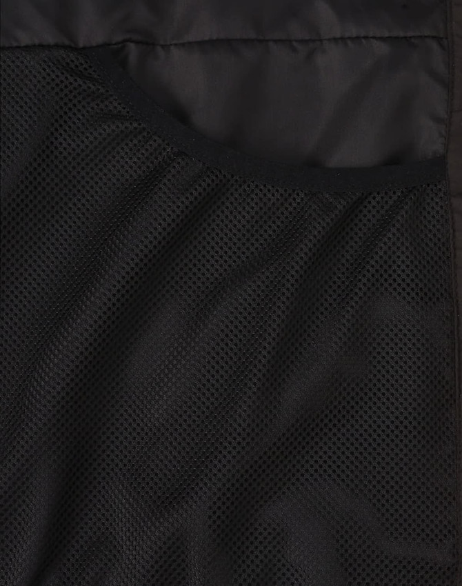 A close-up of a black puffer jacket's inner mesh lining, featuring a pocket and textured fabric.