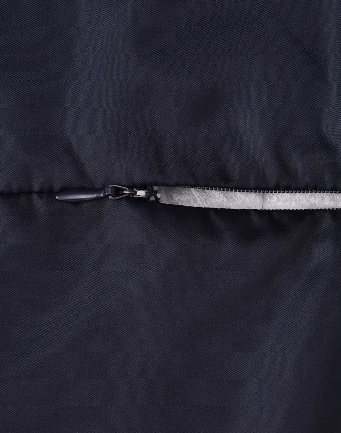 A close-up of a dark puffer jacket featuring a zip closure and a smooth fabric texture. The jacket has a logo.
