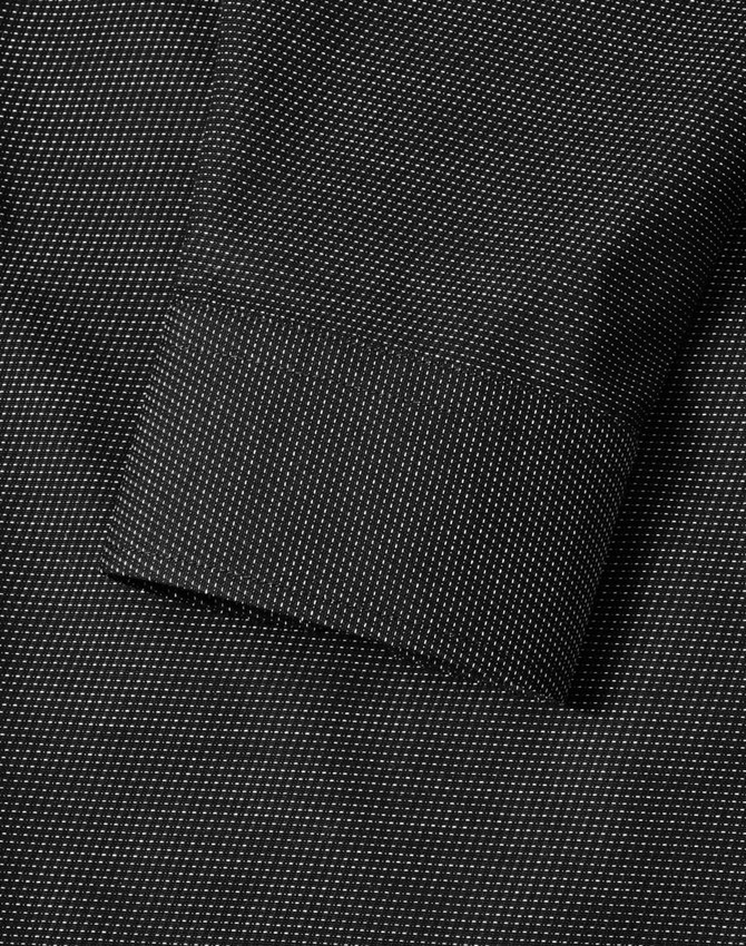 A black pin dot stretch long-sleeve shirt featuring a buttoned cuff and a subtle pattern, with a logo present.