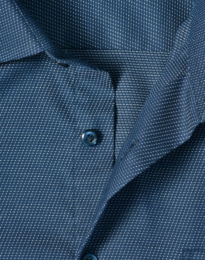 A close-up of a navy blue men's button-up shirt featuring a pin dot pattern and blue buttons.