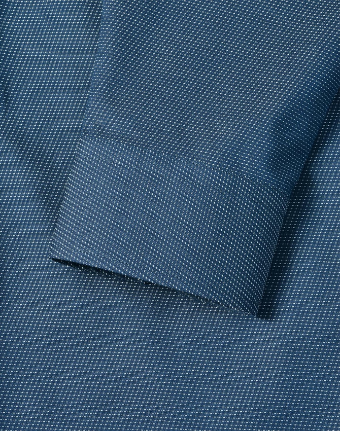 A detailed close-up of a blue men's button-up shirt featuring a pin dot pattern and a cuff.