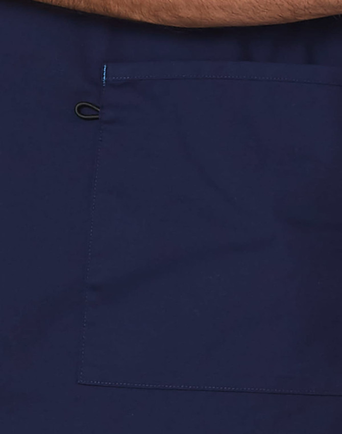 A navy scrub top featuring a large pocket and contrast brown collar. Includes a logo.