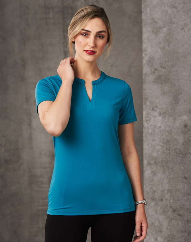 A fitted turquoise ladies' V-neck short-sleeve knit top with a tab design. The model poses against a textured background.