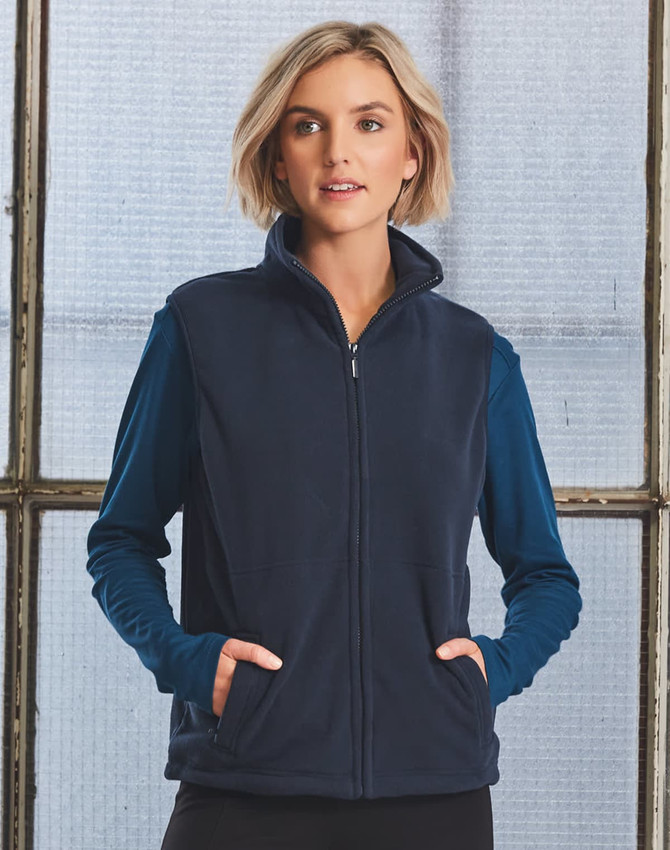 A unisex polar fleece vest in navy, featuring a zip front and side pockets. The model is wearing a long-sleeve top underneath.