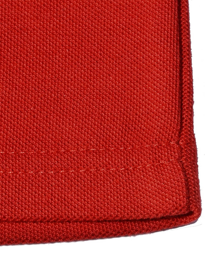 A close-up of a red poly/cotton pique knit fabric, showcasing the texture and stitching of a long sleeve polo shirt.