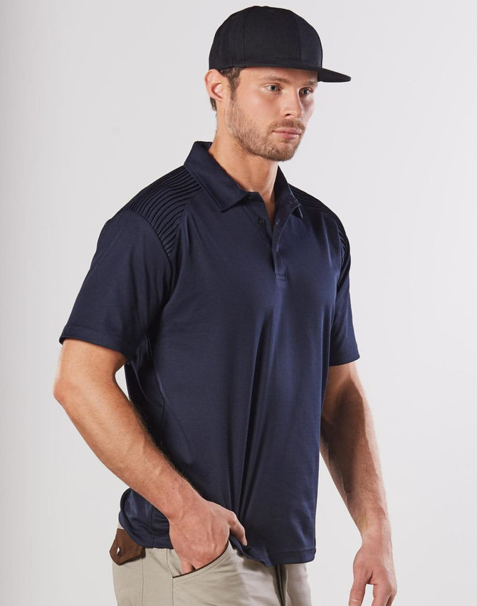 A navy blue polo shirt features textured shoulder detailing and is worn by a man with a cap. The shirt has a logo.