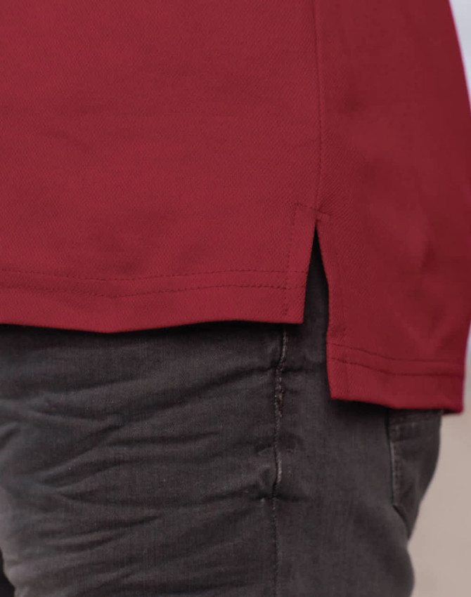 A close-up of a burgundy long sleeve polo shirt, featuring side slits for ease of movement.