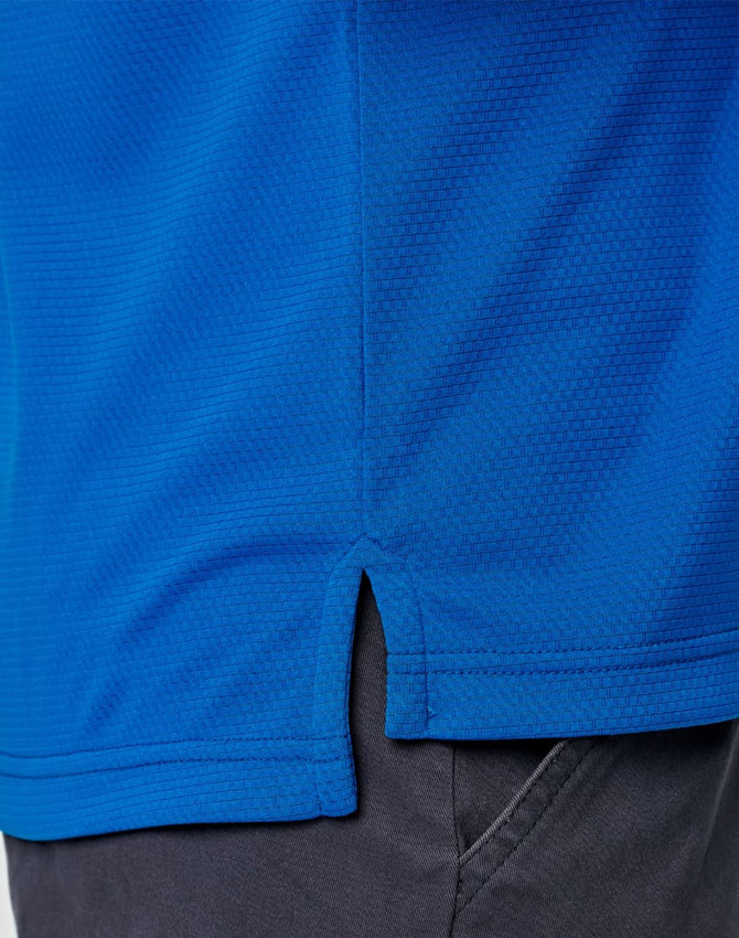 A close-up of a blue polo shirt with a side vent detail, featuring a logo at the chest area.