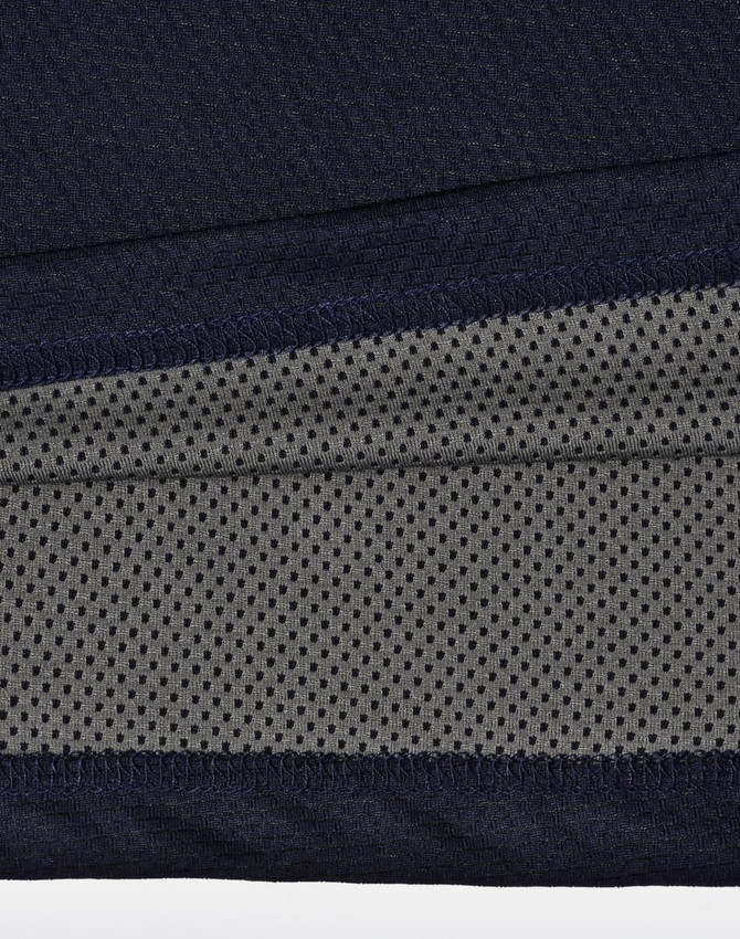 A close-up of a navy and charcoal polo shirt, featuring a textured fabric and a logo.