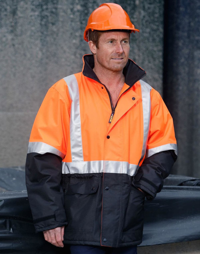 A hi-vis orange and black quilted safety jacket with reflective strips, worn by a person in an orange hard hat.
