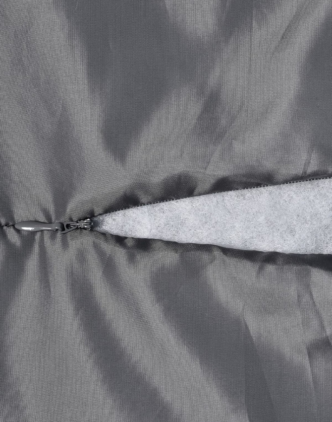 A close-up of a grey quilted fabric featuring a zippered section and a soft, light grey lining.