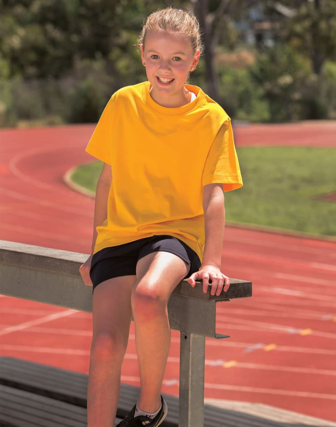 A bright yellow semi-fitted cotton t-shirt on a girl sitting on a bench near a running track.