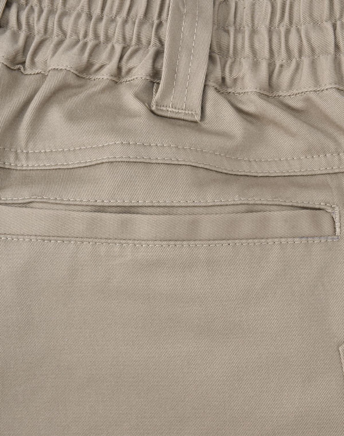 A close-up of beige unisex cotton stretch drill work shorts, featuring an elastic waistband and a pocket.