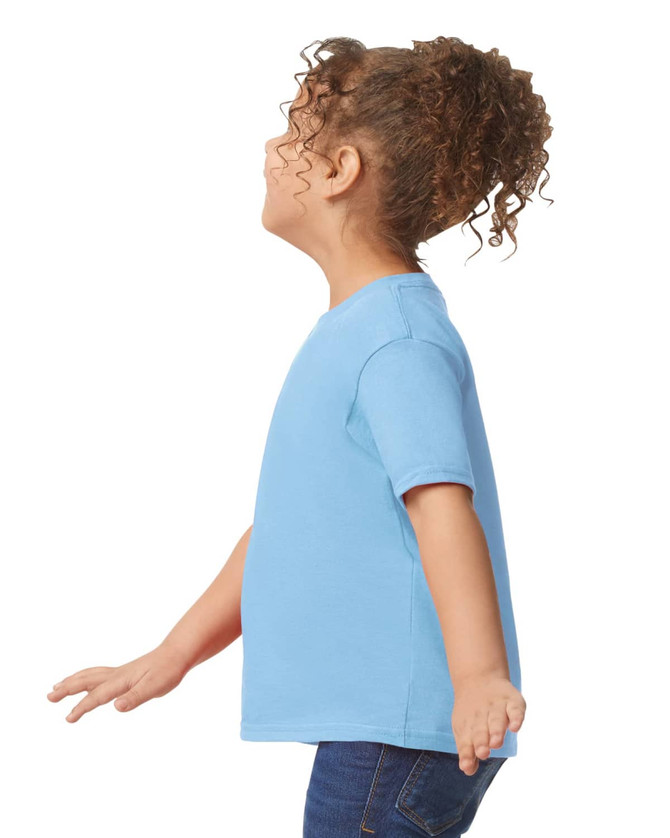 A toddler wearing a light blue Gildan Heavy Cotton T-Shirt, displayed from the side with curly hair.