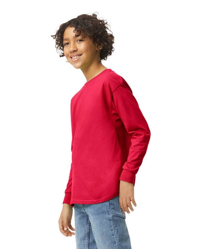A youth long sleeve t-shirt in bright red, featuring a logo, displayed on a young person smiling.