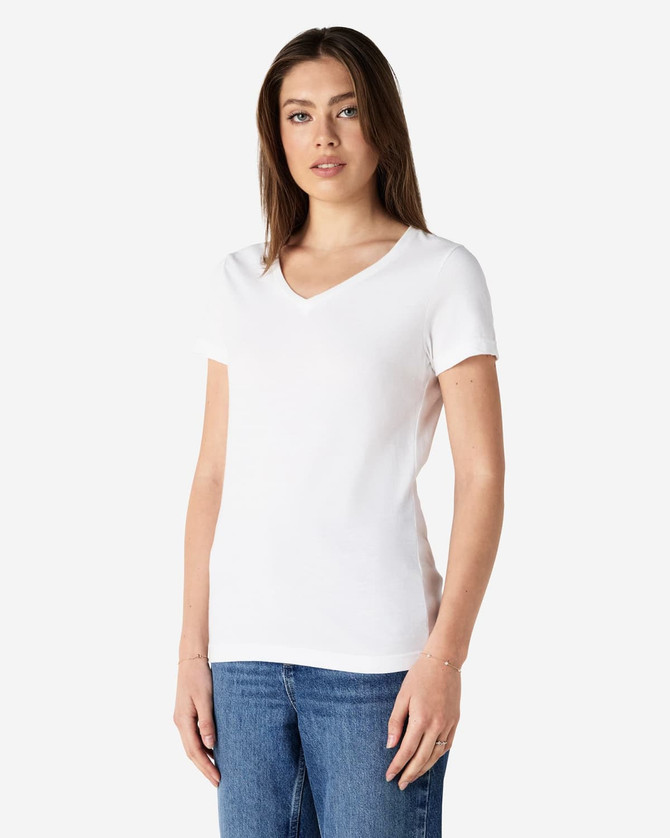 A white Gildan Softstyle ladies' V-neck T-shirt displayed on a model, paired with blue jeans. Features a logo.