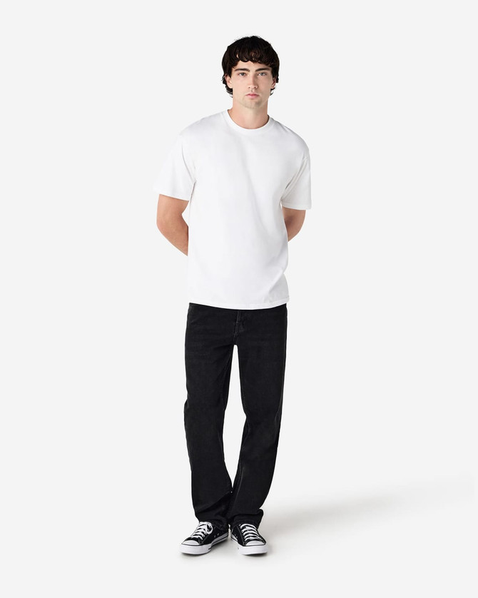 A model wearing a plain white Gildan Hammer adult t-shirt, paired with black jeans and sneakers, standing against a neutral background.