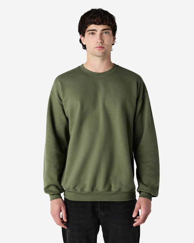 A green Gildan Softstyle adult sweatshirt, featuring a classic crew neck and long sleeves. The model stands facing forward.