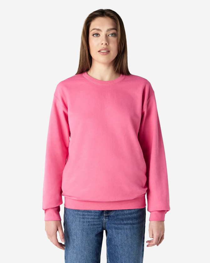 A pink Gildan Softstyle adult sweatshirt is worn by a model, paired with blue jeans. The sweatshirt has a logo.