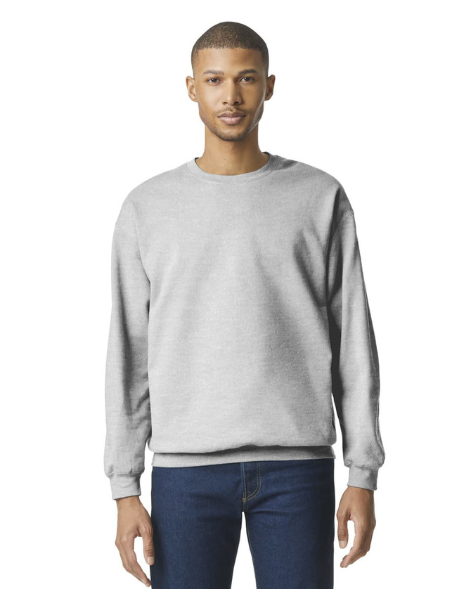 A grey Gildan Softstyle adult sweatshirt worn by a model, featuring a round neckline and long sleeves.