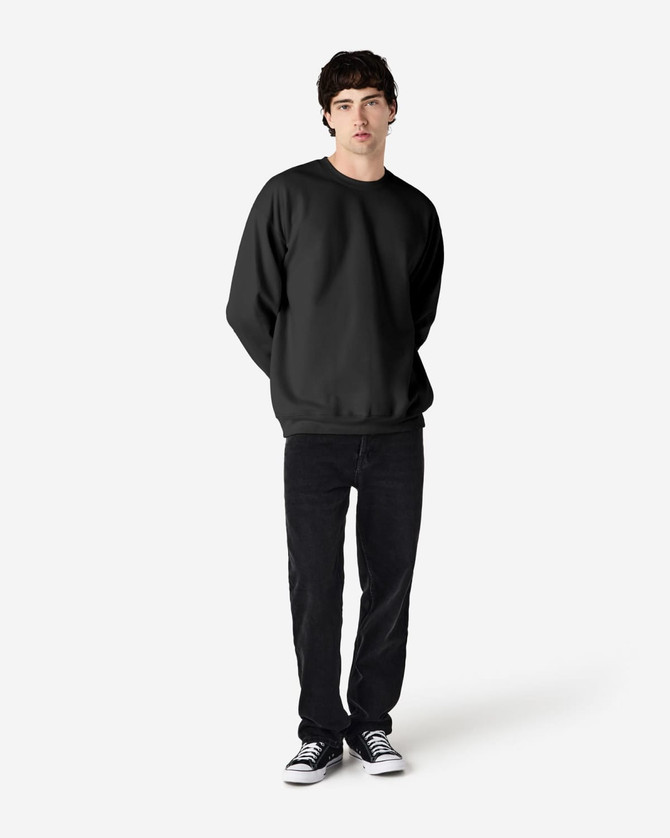 A young man wearing a black Gildan Softstyle adult sweatshirt, paired with black jeans and sneakers.