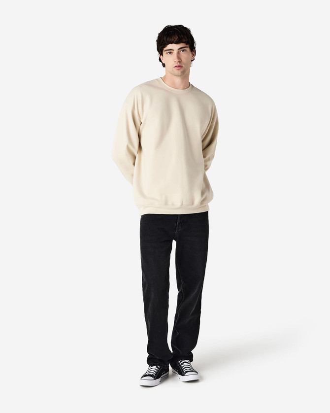 A cream-coloured Gildan Softstyle adult sweatshirt displayed on a model, paired with dark jeans and sneakers.