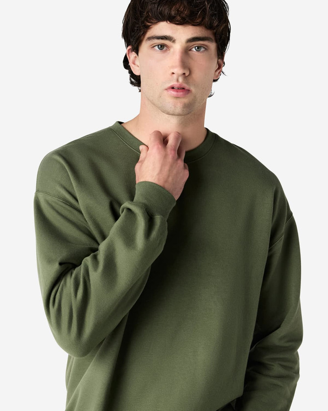 A model wearing an olive green Gildan Softstyle adult sweatshirt. The sweatshirt has a round neckline and long sleeves.