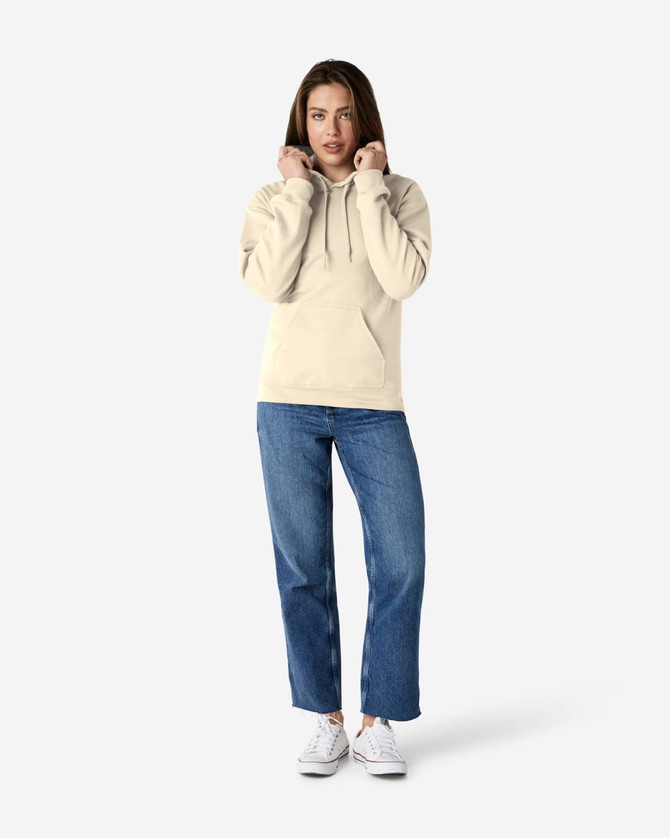 A hooded sweatshirt in cream worn by a person, paired with blue jeans and white shoes. The sweatshirt has a logo.