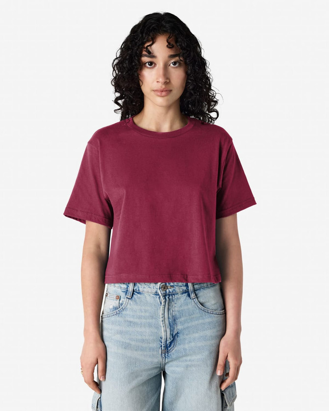 A boxy maroon T-shirt is displayed on a model, paired with light blue jeans. The shirt has a logo.