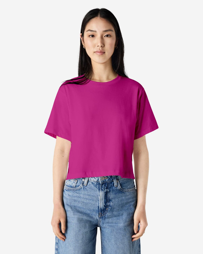 A vibrant fuchsia women's boxy T-shirt with a relaxed fit, paired with light blue jeans. Features a branding logo.