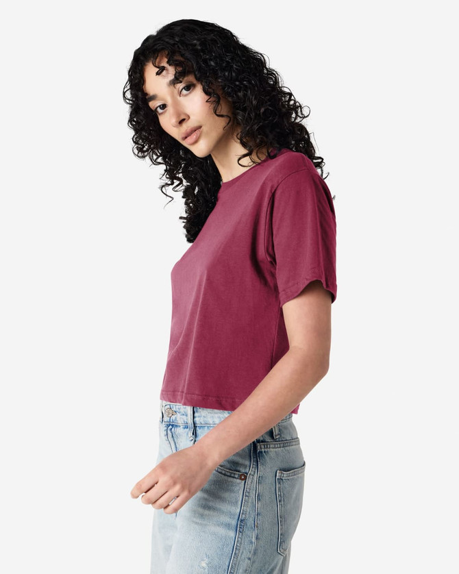 A maroon women's fine jersey boxy t-shirt displayed on a model with curly hair, featuring a casual fit.