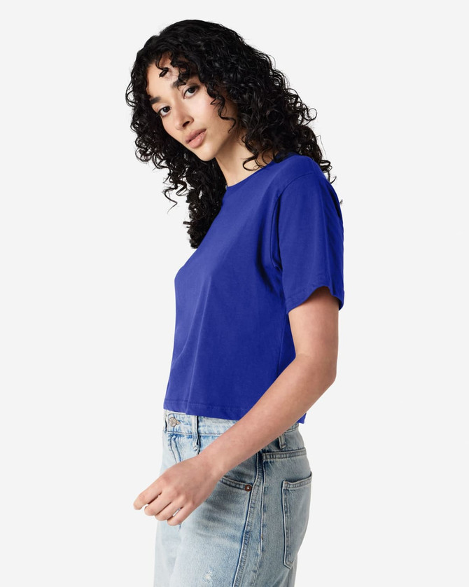 A blue boxy T-shirt with short sleeves, displayed on a model wearing jeans. The shirt has a logo.