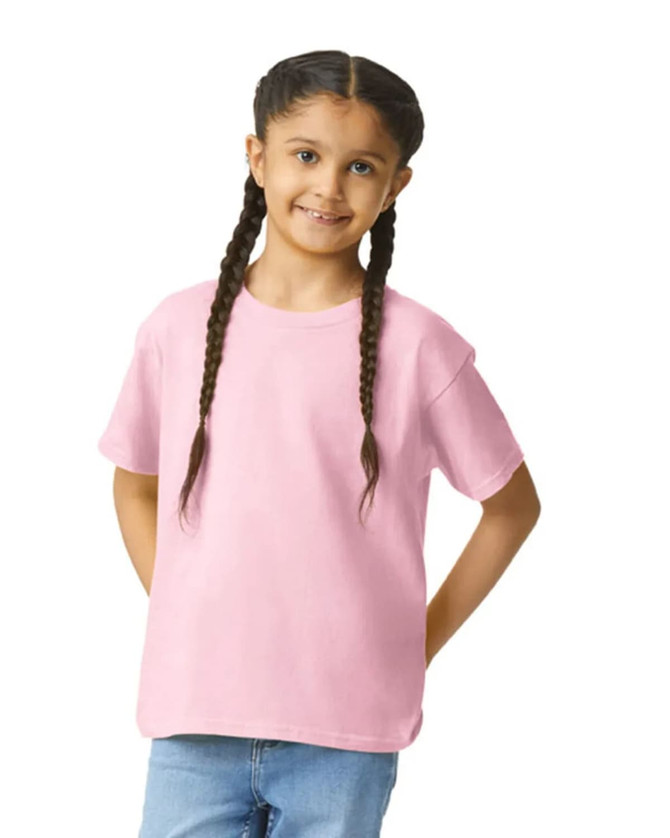A youth softstyle short sleeve t-shirt in pink, worn by a girl with braided hair, smiling at the camera.
