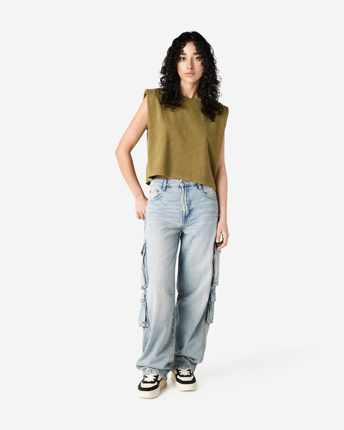 A woman is wearing an olive green muscle T-shirt paired with light blue baggy jeans. The outfit has a casual style.