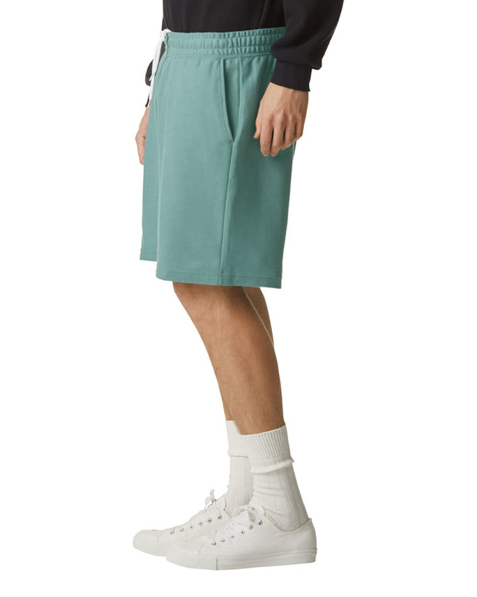 Unisex gym shorts in teal with pockets and a drawstring waistband, worn with white sneakers and socks.