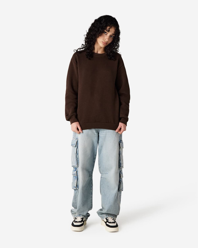 A unisex crewneck sweatshirt in brown worn with light blue cargo pants, featuring a simple design and a logo.