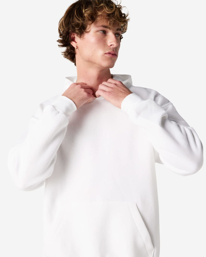 A unisex hooded sweatshirt in white, featuring a pocket and a logo on the front. The model adjusts the collar.