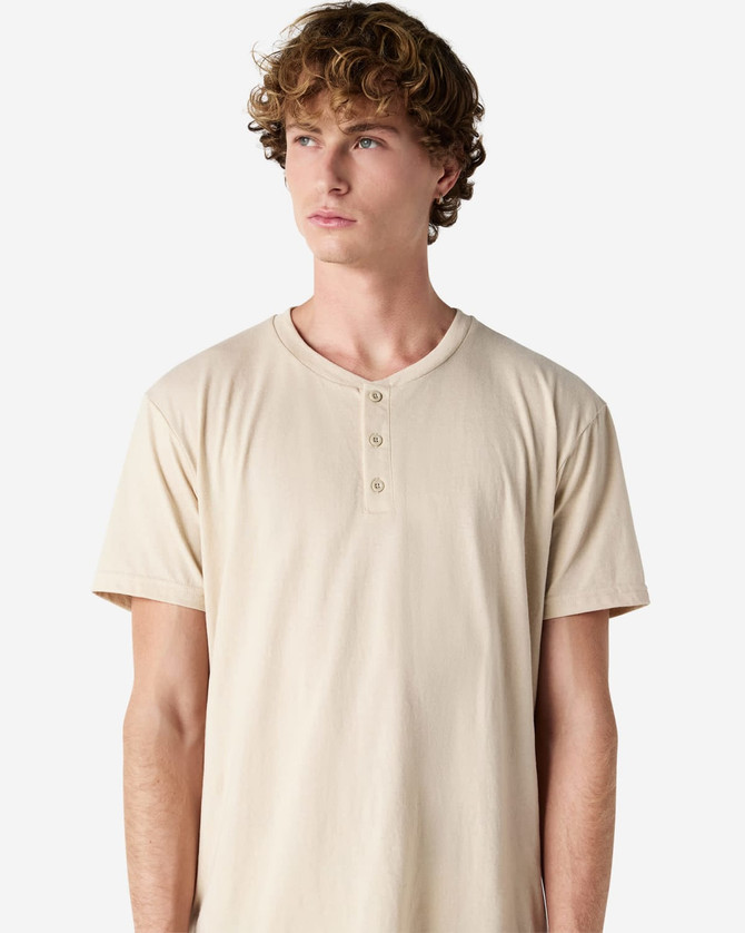 A unisex henley t-shirt in a light beige colour, featuring three buttons at the neckline and short sleeves.
