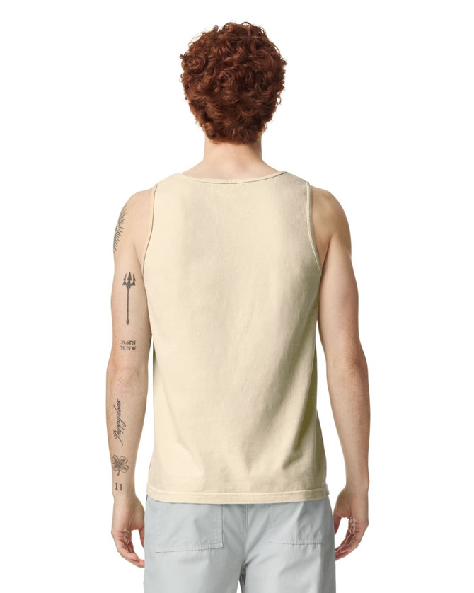 A light beige tank top on a model, featuring a plain back and a visible logo at the neckline.