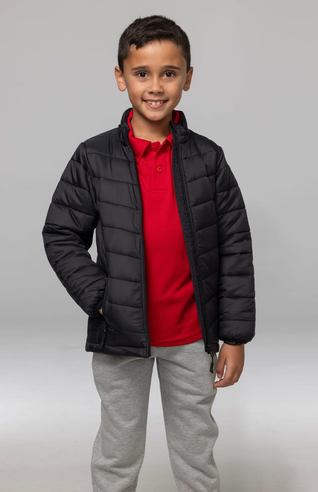 A child wearing a black insulated jacket over a red polo shirt, paired with grey pants. The jacket features a logo.
