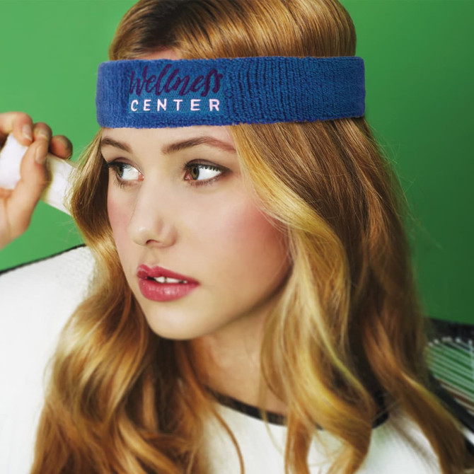 A blue head sweat band worn by a woman with long hair, set against a green background. The band features a logo.