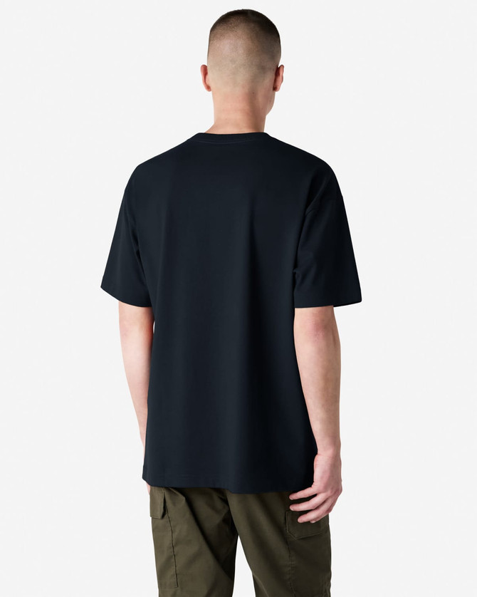 A black American Apparel Super Heavyweight T-Shirt viewed from the back, paired with olive green trousers.