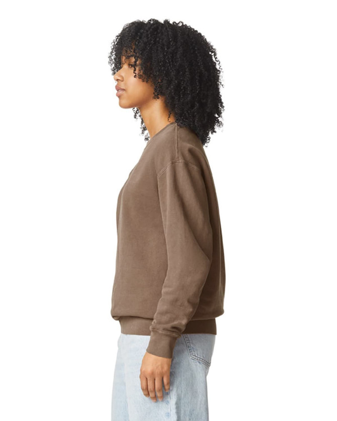 A brown crewneck sweatshirt with a relaxed fit, featuring a side view of a model. It has a logo on the sleeve.