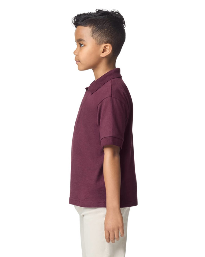 A youth polo shirt in burgundy, featuring a collar and short sleeves, shown on a child from the side.