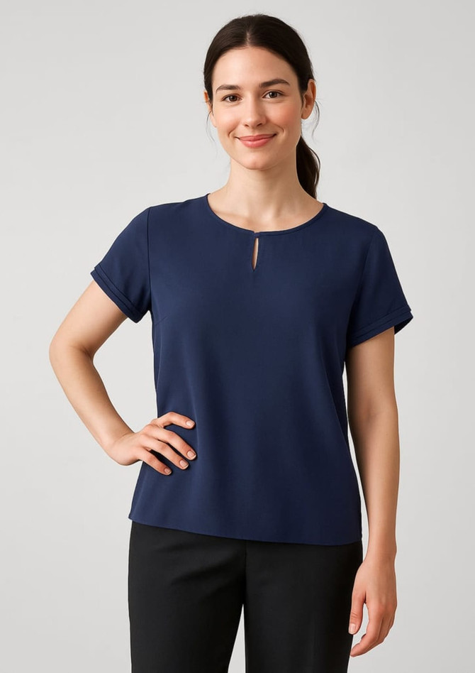 A navy blue short sleeve blouse with a keyhole detail at the neckline, displayed on a smiling model.