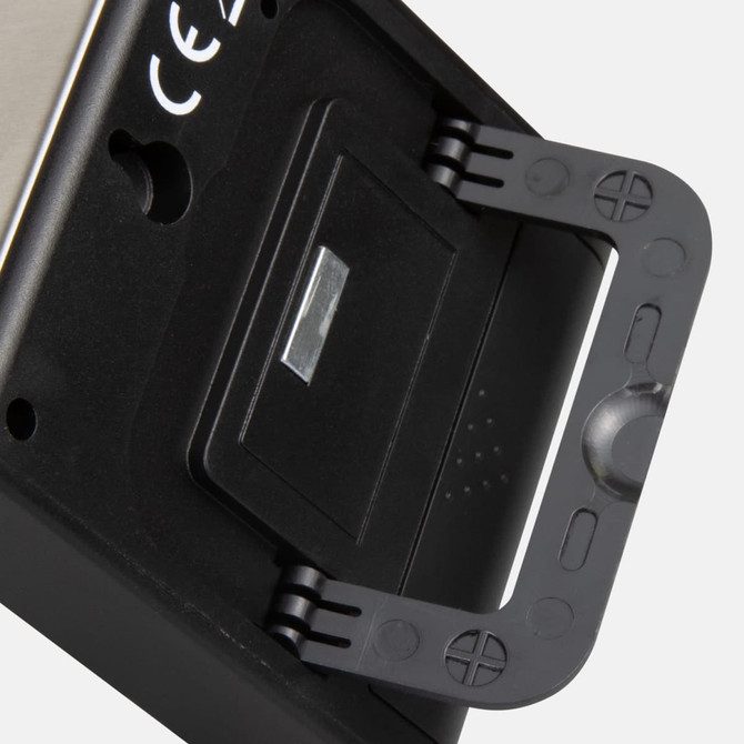 A black kitchen timer with a stand, featuring a metallic back and a small flip cover. It has a logo on the side.