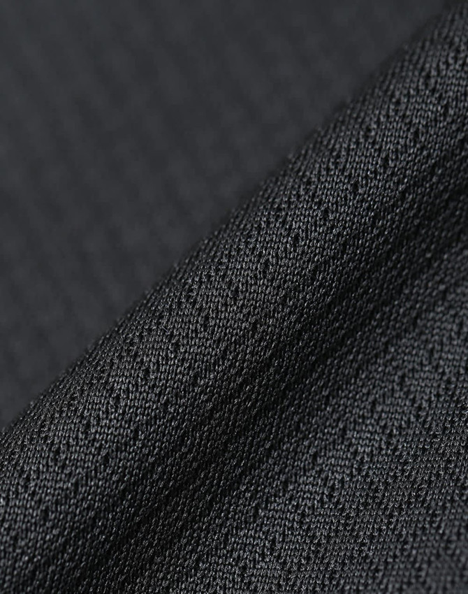 A close-up of textured black fabric, showcasing a sustainable jacquard knit pattern. Featuring a subtle sheen, it has a fabric brand logo.