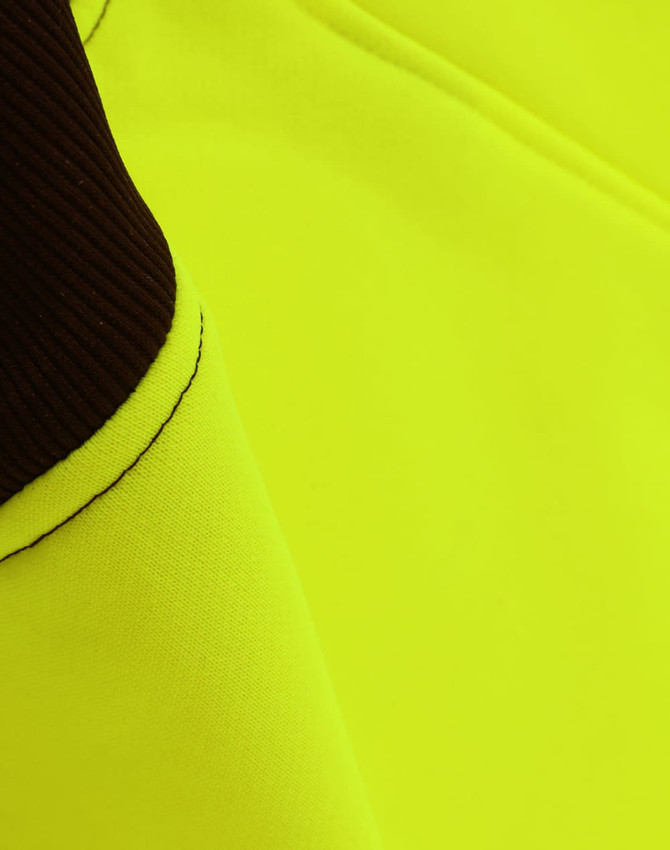 A close-up of a bright yellow fleece fabric with dark brown accents, featuring a logo.