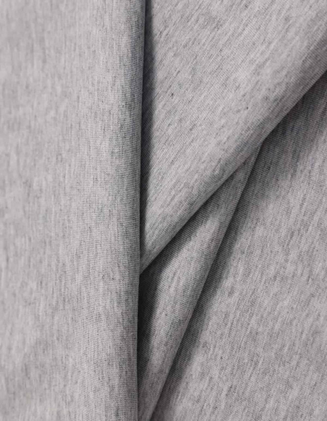 A close-up of light grey cotton fabric, showcasing its soft texture and smooth finish. The fabric has a logo.