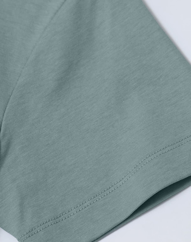 A close-up of a light blue short-sleeve cotton T-shirt with a smooth finish and a small logo.